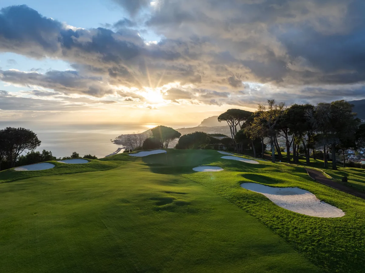 A green at Palheiro Golf at golden hour, high above Funchal Bay and the Atlantic